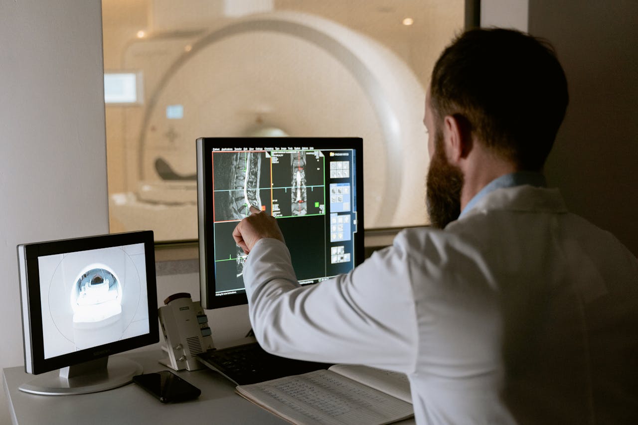 Medical professional reviewing MRI scans on computer screens for diagnostic purposes.